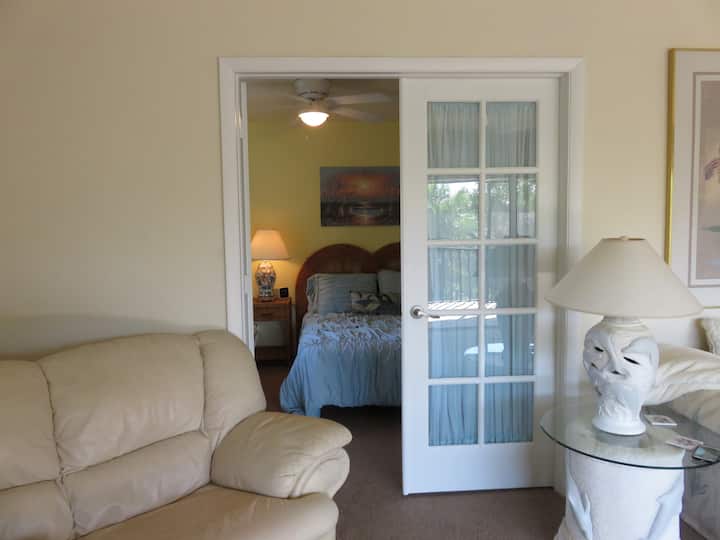 Wohnzimmer mit Blick in ein voll ausgestattetes Schlafzimmer.