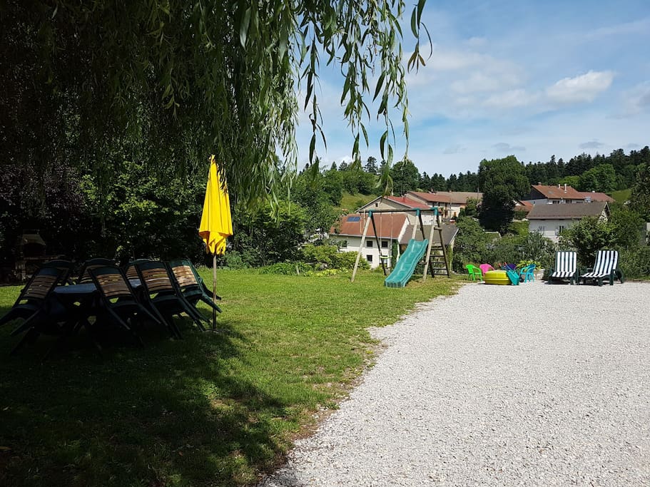 Terrain derrière la maison avec table,barbecue, balançoire, bac à sable, chaises longues
