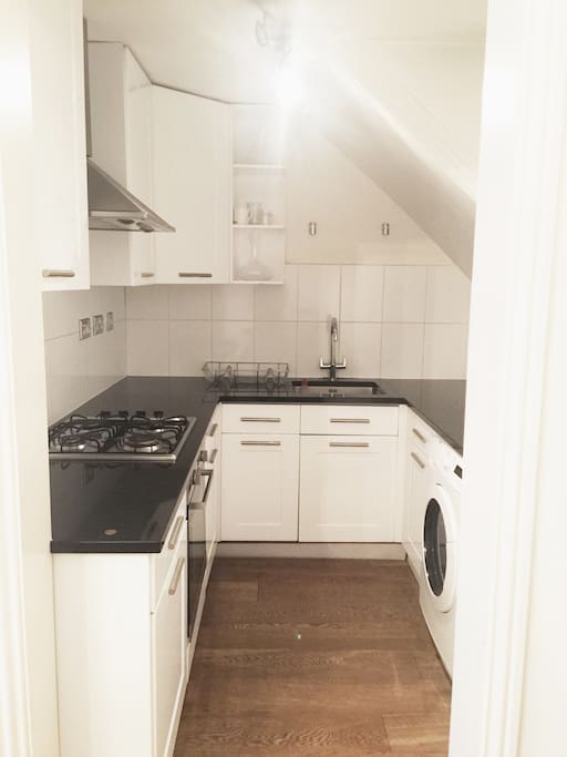 Tidy kitchen with cutlery, pans and cooking utensils for use.