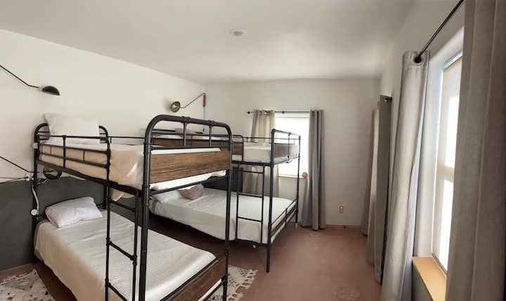 Dormitorio con una litera tamaño queen y un juego de literas individuales.