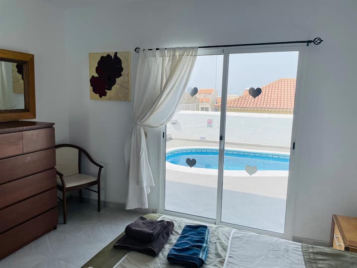 غرفة نوم بسرير بمقاس كبير وحمام داخلي يؤدي إلى منطقة حمام السباحة