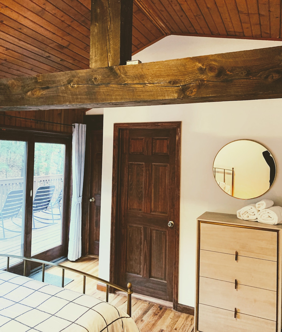 غرفة النوم 1: سقف مغطى بالألواح الخشبية وعوارض مستصلحة مكشوفة. يؤدي الباب إلى حمام خاص.