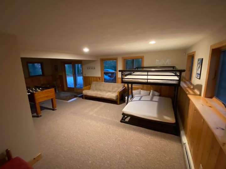 Това е отворената сутеренна стая, характеризирана като „Спалня 4“.  Това е ПЪЛНО легло, както и сгъваем футон до него.  Зад ъгъла е основната зона за забавления в мазето с разтегателен диван и телевизор, монтиран на стената.   