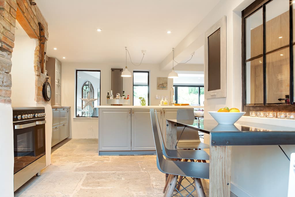 Contemporary kitchen with wine cooler, range cooker, breakfast bar, table & chairs.