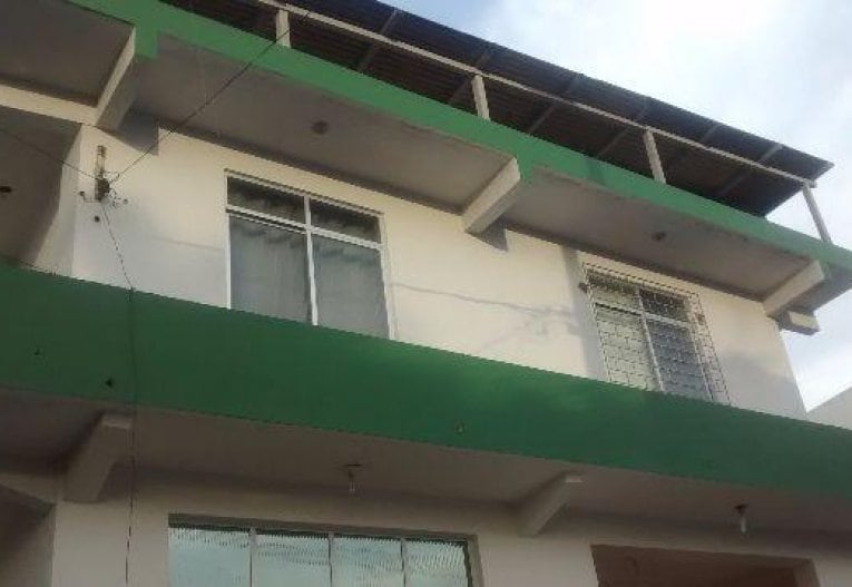 The building features a modern architectural design with a two-tone exterior. Large windows allow natural light to fill the interior. A covered terrace is present on the upper level, providing outdoor space. The clean lines and open structure enhance the overall look.