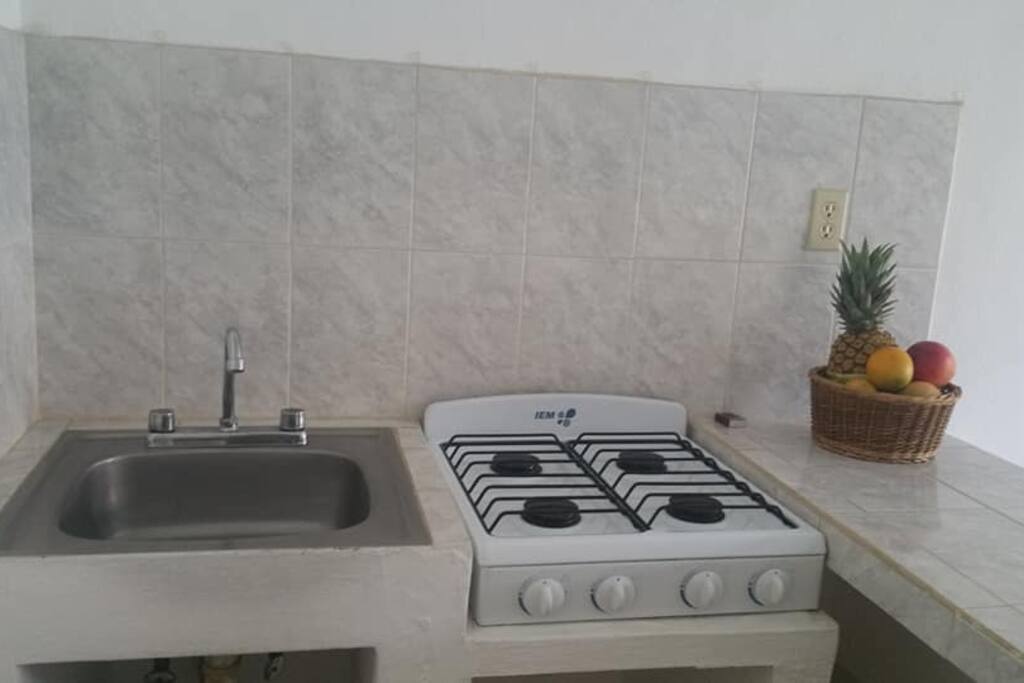 Cocina con refrigerador, estufa y lavabo.