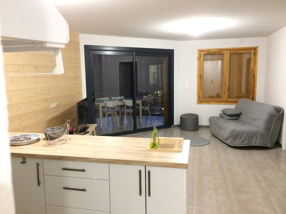 pièce à vivre espace cuisine et salon TV et loggia entièrement vitrée avec vue montagne