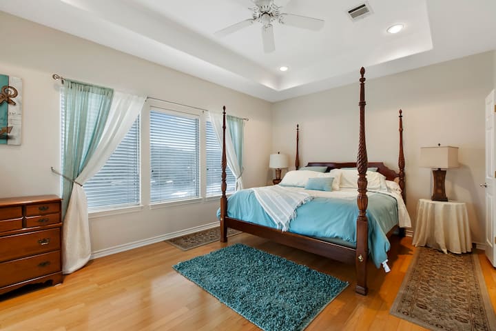 Spacious primary bedroom with nightstands, dresser, and ceiling fan