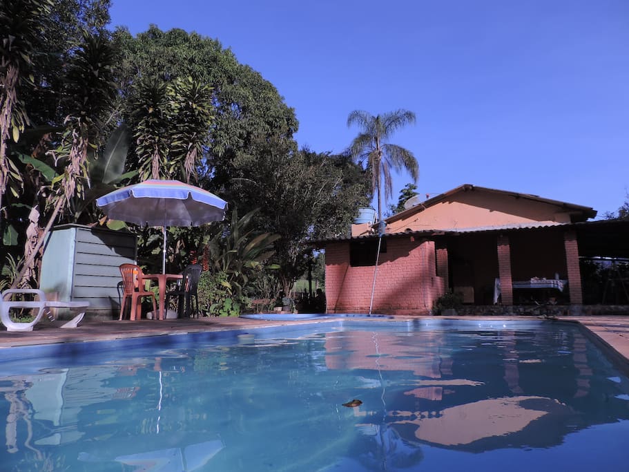 Área de lazer da piscina e casa principal ao fundo