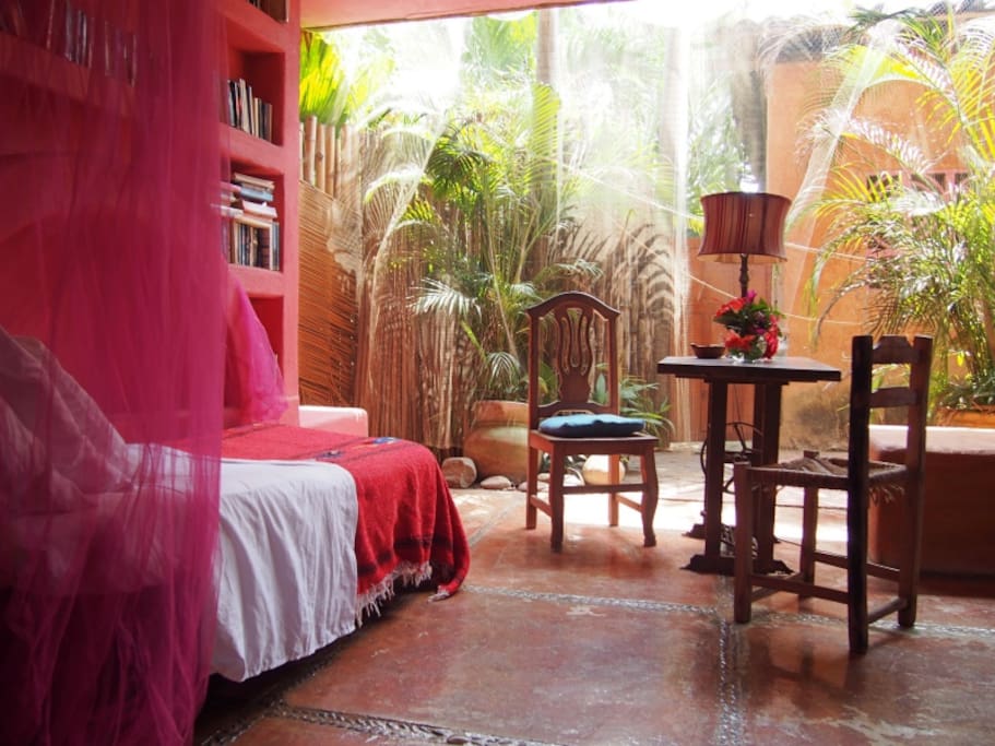 The Red Mermaid Suite - ground floor, a queen bed in its inner area and a large 'L' shaped private covered terrace with two cushioned benches used as extra beds