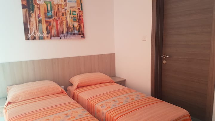 غرفة نوم ثانية بسريرين فرديين يؤديان إلى شرفة جانبية. 