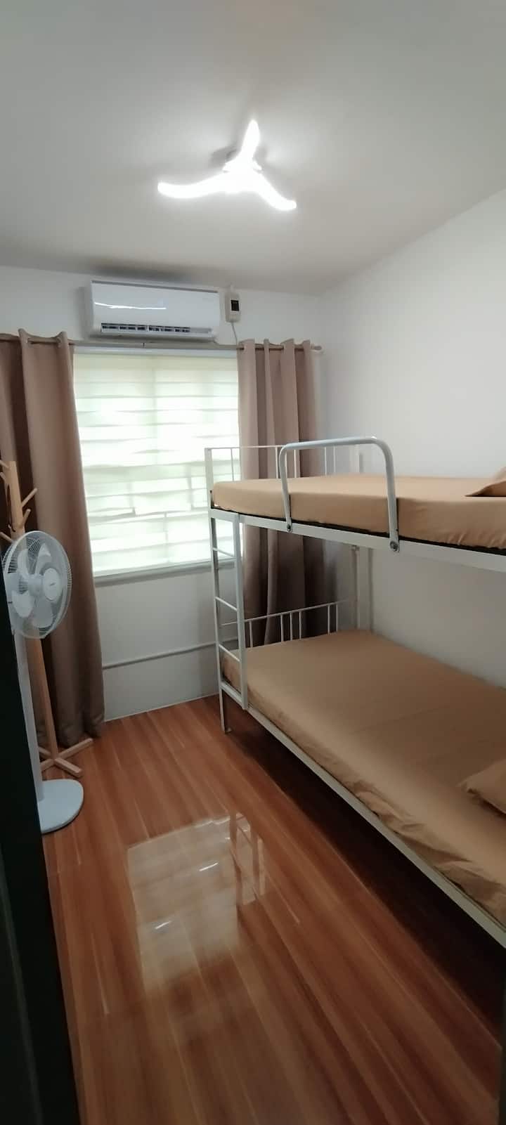 3. spálňa. Jednolôžko na poschodovej posteli. 1 energeticky úsporná invertorová klimatizácia, stojanový ventilátor, prenosný stolík na notebook a vešiak na oblečenie.

Zatemňovacie závesy pomáhajú spať kedykoľvek počas dňa.

D2,4 m x 2,15m