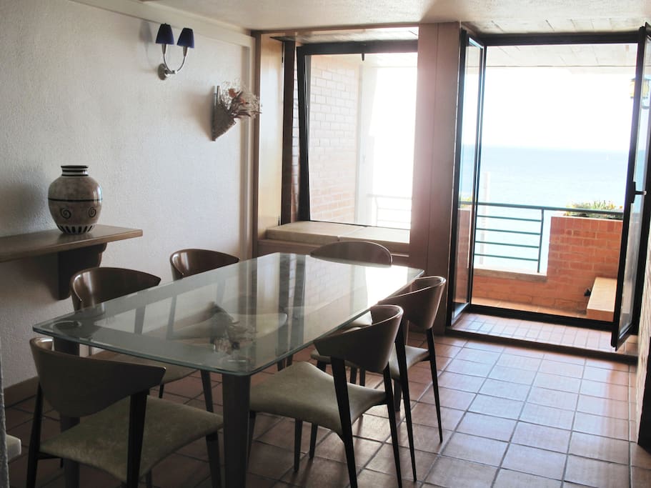Sala de jantar junto à varanda com mesa de vidro e 6 cadeiras.