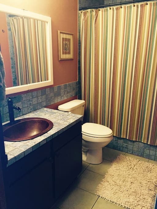 Shared bathroom with copper sink and jetted tub and shower