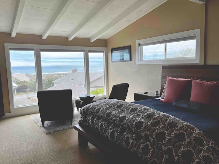 Голема главна спална соба со апартман со кревет Cal King и поглед кон океанот и простор за седење. 