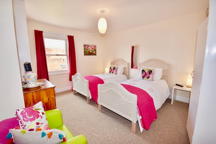 La "habitación rosa" con camas individuales y cortinas opacas junto al baño familiar y el dormitorio Super King.