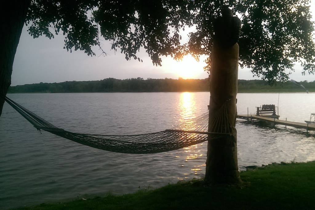 Lakeshore view with hammock, paddle boat and dock.