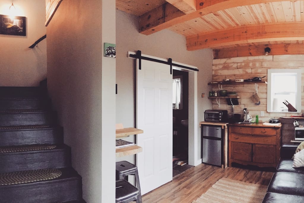 The living room and kitchenette, stairs lead up to the bedroom.