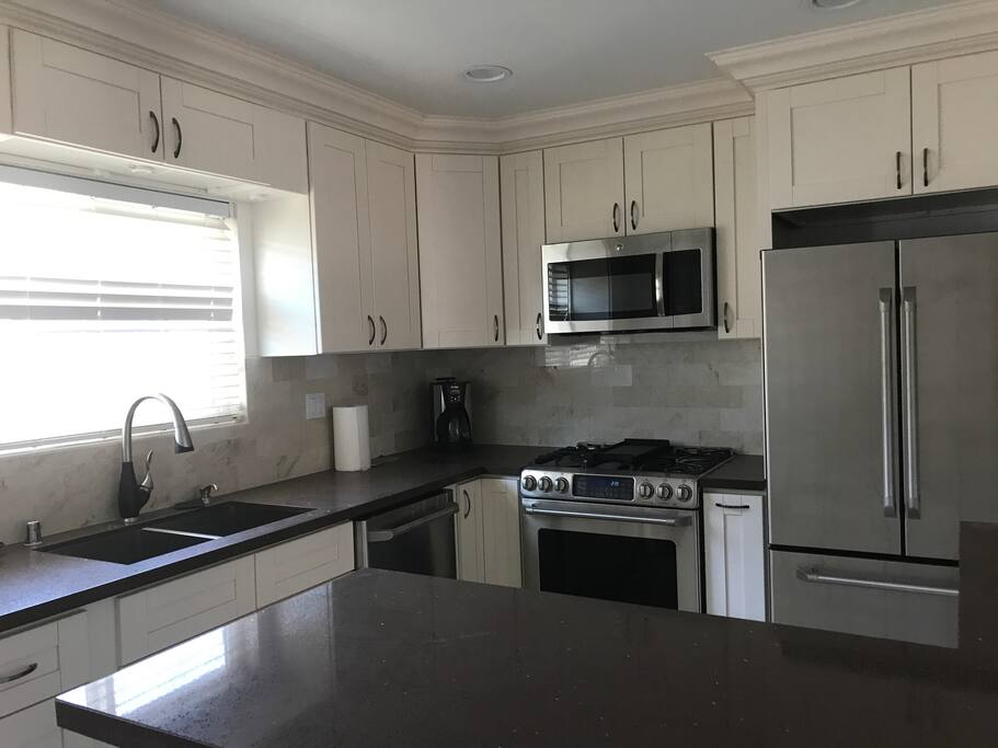 Fully renovated kitchen with stovetop, oven, microwave, coffee maker, and fridge/freezer
