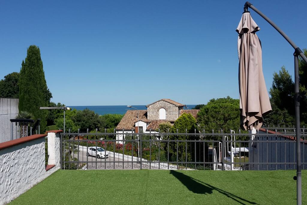 Solarium terrazzo superiore ad uso esclusivo con bellissima vista mare, alberi intorno e manto erboso sintetico