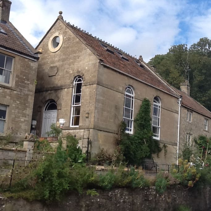 The house is set on a high pavement opposite the village school.