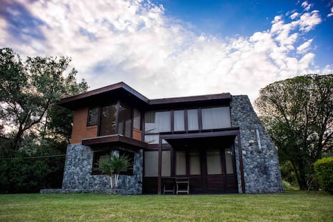 Large house near the sea, surrounded by forest.