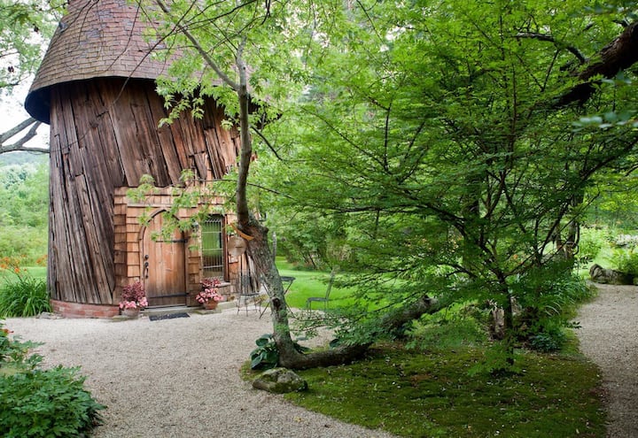 A unique New England Airbnb is seen as a wooden tower on a tree lined path