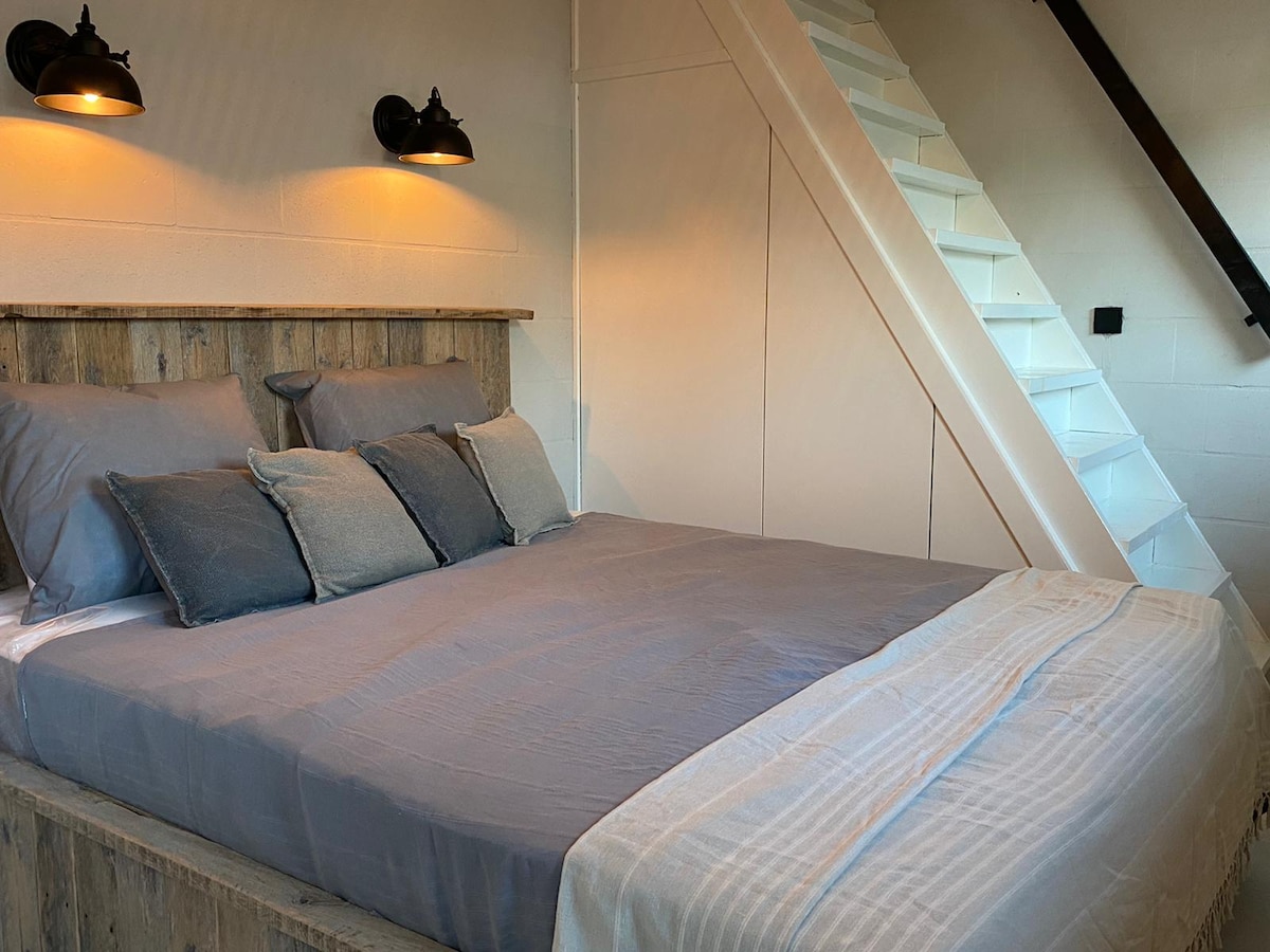 Dormitorio 1 con escaleras al dormitorio 2. Este es el dormitorio de la planta baja. Amueblado con estilo con un armario al lado de la cama. Dormir o levantarse temprano para dar un paseo, ¡hay algo para todos!