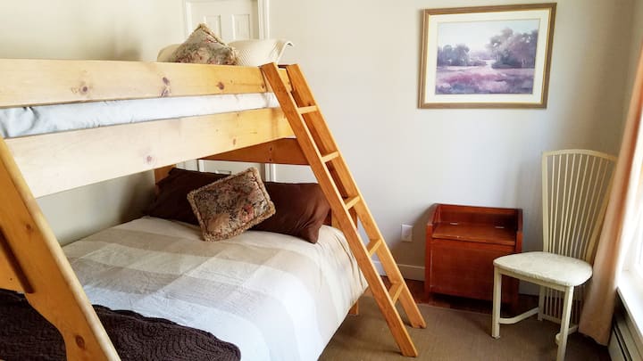 Dormitorio con literas, con cama completa en la parte inferior y dos camas individuales en la parte superior.