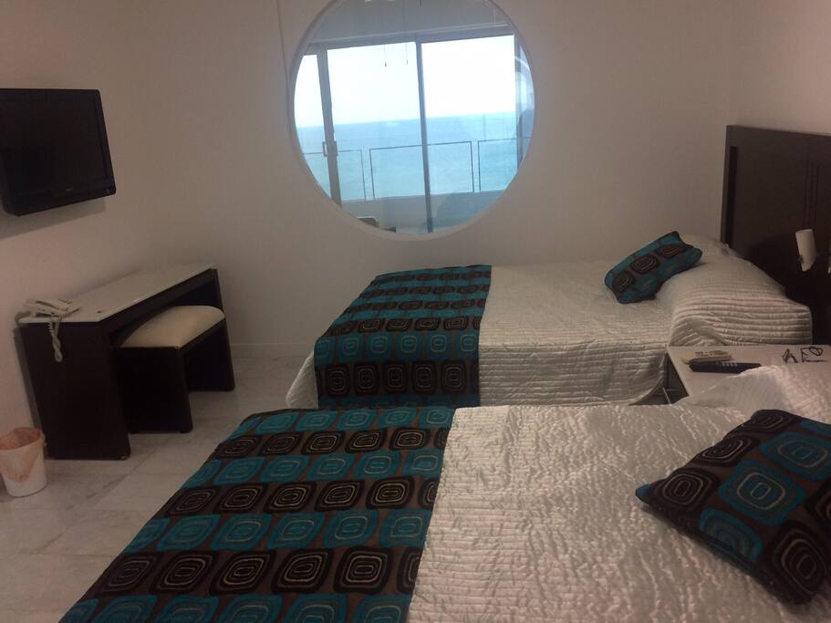 Máster suite, con dos camas matrimoniales, closet, mesa de trabajo, aire acondicionado, pantalla con cable, ventilador de techo, vista al mar.
