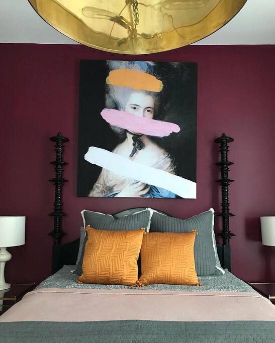 Queen size spire bed featuring luxury linens and a dramatic brass drum light fixture.