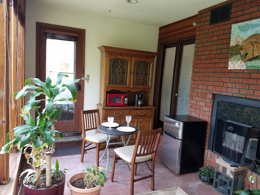 Private entrance into a sun room with small fridge/freezer, microwave, coffee maker, heater, small eating area, and hot tub.