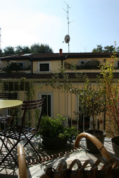 A relaxing terrace with a rocking chair and a table surrounded by Mediterranean plants.