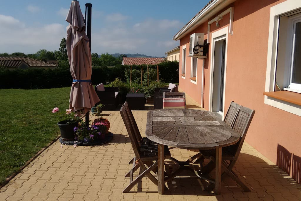 la terrasse avec la table et le petit salon de jardin derrière. en fond, le potager