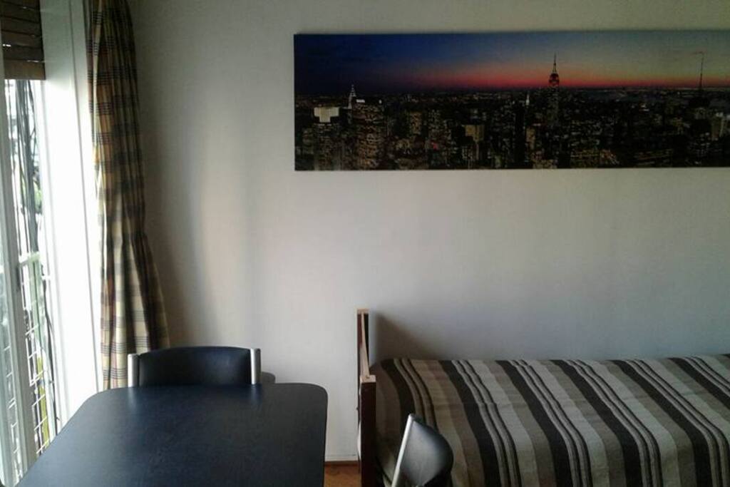 Living comedor. Cama de una plaza con cama desplegable abajo, mesa y 4 sillas (mas 2 banquetas)