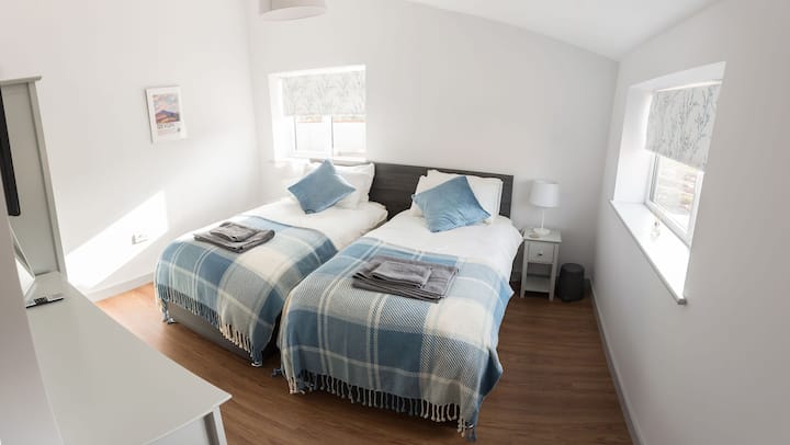 חדר שינה שני.  בכל החדרים יש אפשרות זוגית זוגית זוגית בגודל קינג סייז. ארון בגדים, שידות ליד המיטה עם מנורות ושולחן הלבשה עם מגירות.  מראות על שולחן ההלבשה ועל הקיר. טלוויזיה חכמה.