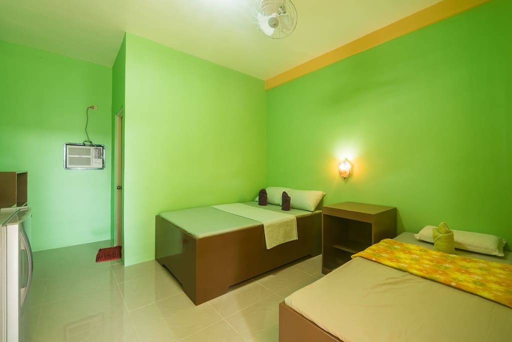 Inside view of the rooms with fridge, beds, aircon and ceiling fan system