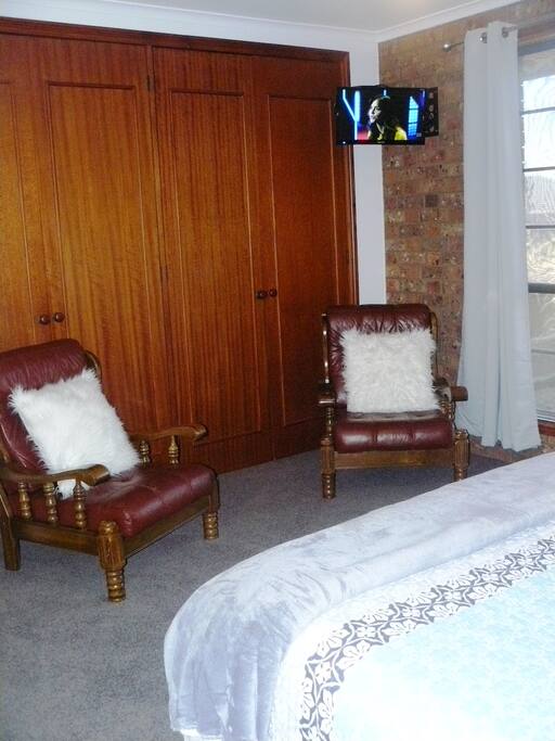 TV plus two armchairs in bedroom