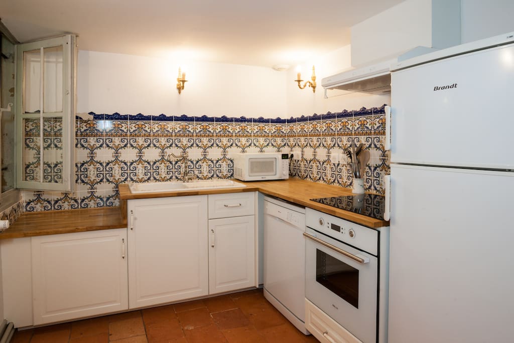 Charming French kitchen with white cabinets and wood countertops in a historic 1600's Carcassonne vacation rental. #Frenchkitchen #classic #France #apartment