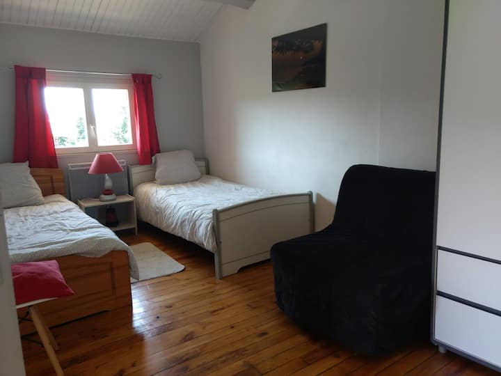 החדר עם 2 מיטות יחיד וכורסת אחת, מושב אחד, מלתחה אחת, שולחן ליד המיטה.