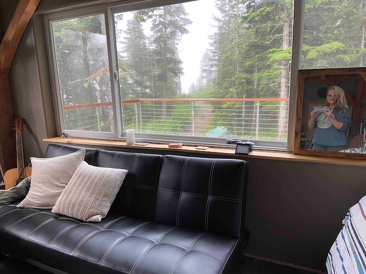 Okno s otváraním 10 stôp cez prednú stranu obývacej izby.  Veľké okná v celom objekte.  Výhľad zo všetkých strán.  Čierny cvakací gauč sa vysúva a vytvorí ďalšiu posteľ.  