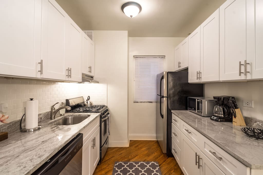 Kitchen - Stainless steel appliances, shaker-style cabinets, and white granite, equipped with essentials.