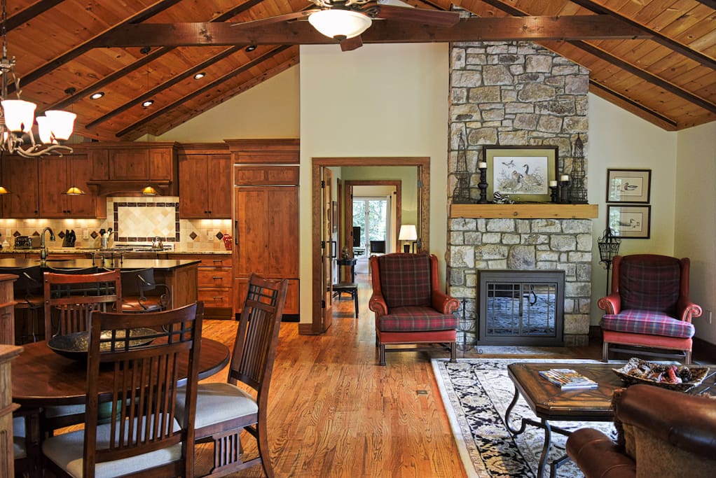 Featuring a vaulted ceiling with exposed beams, the open floor plan of the home allows for a large living room area, where the unique two-sided stone fireplace is ready to light. #fireplace