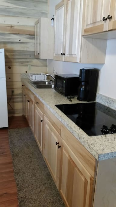 Kitchen with microwave, coffee pot, and stove top.