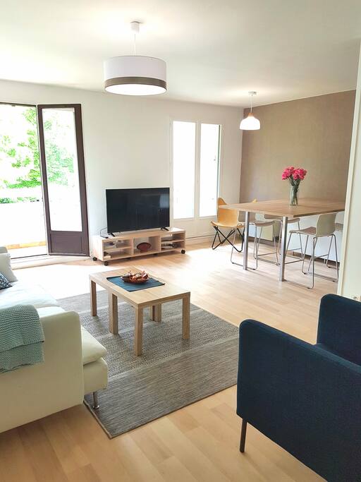 Salon spacieux ouvert sur balcon, salle à manger et cuisine.