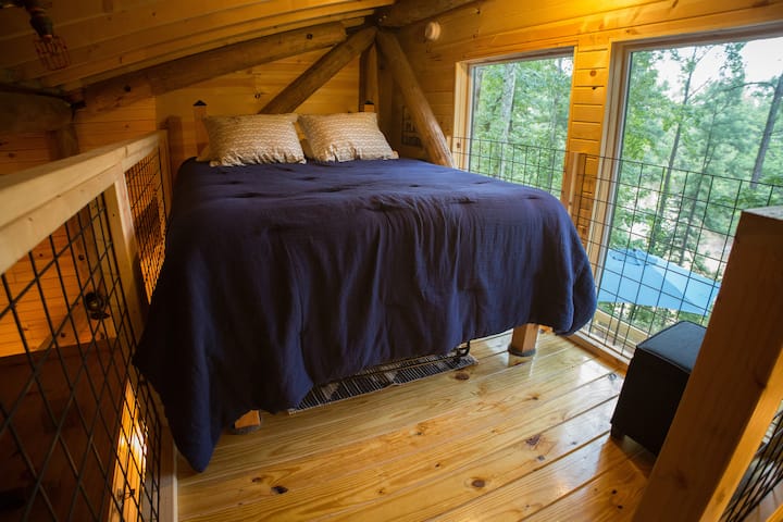 The loft features a custom made queen size bed, memory foam mattress, deluxe linens and pillows,  USB outlet, under bed storage, and great views of nature.