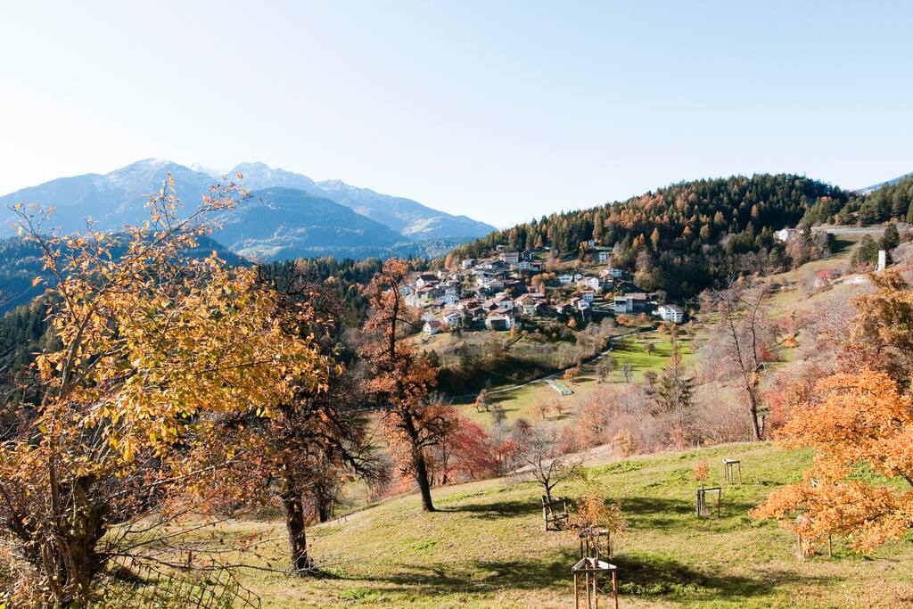 Garten und Sitzplatz mit Tischgarnitur, Smoker und Liegestühlen an einem sonnigen Hang mit Blick in die Berge