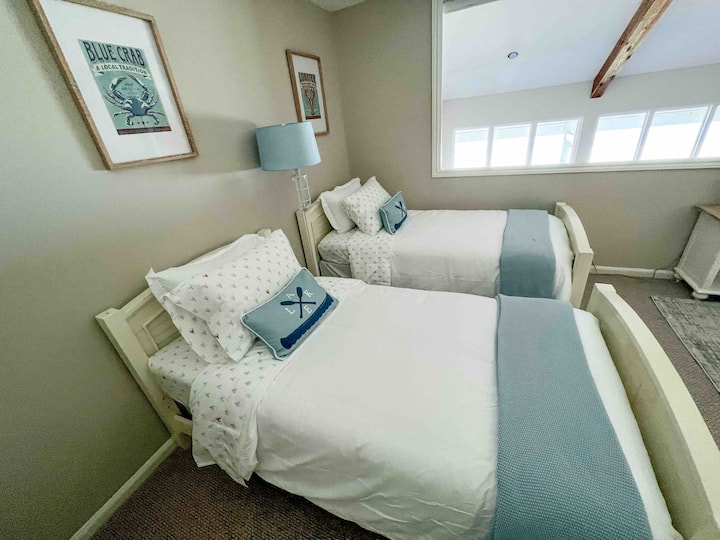 Vitanda viwili viwili katika chumba cha kulala cha roshani kinachoangalia sebule na ziwa. 