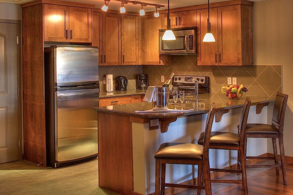 This sleek kitchen has stainless steel appliances and a breakfast bar.