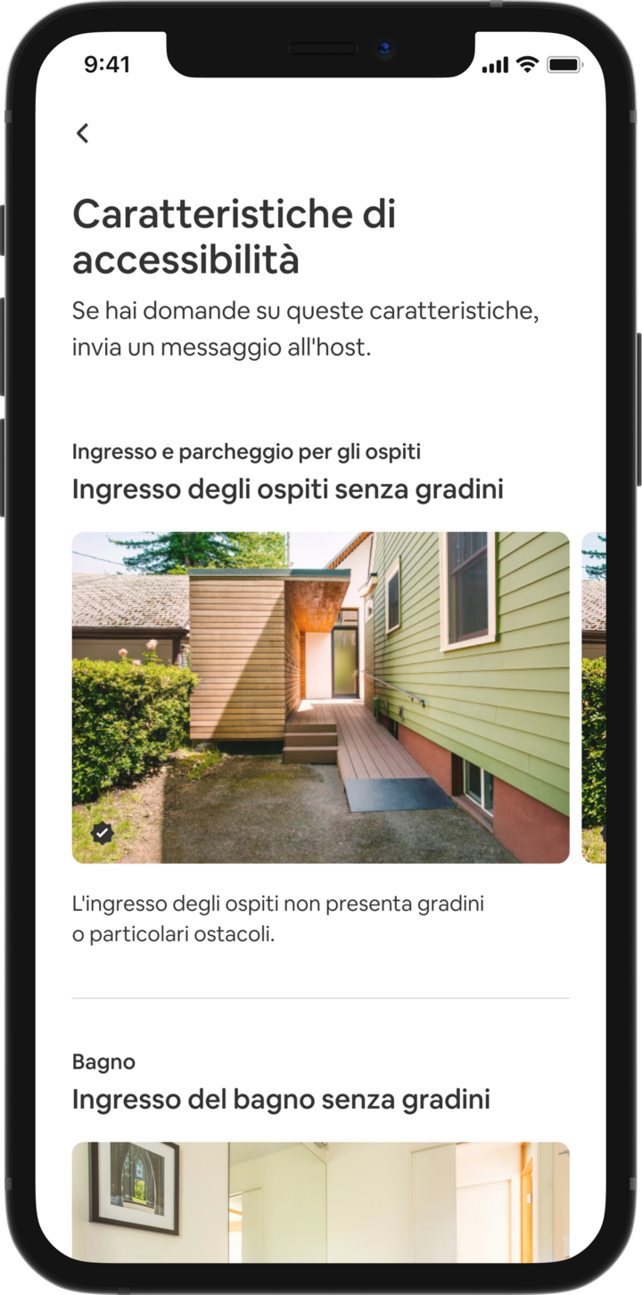 Un telefono cellulare mostra i dettagli dell'alloggio di un annuncio su Airbnb. Il titolo principale recita "Caratteristiche di accessibilità" e queste sono raggruppate per area, come "Ingresso e parcheggio per gli ospiti" e "Bagno". Sotto "Ingresso e parcheggio per gli ospiti" si trova il titolo "Ingresso per gli ospiti senza gradini" e la descrizione della caratteristica "All'ingresso per gli ospiti non ci sono gradini o grandi soglie." Sotto si trova una presentazione in cui scorrono le fotografie della caratteristica dell'alloggio, che inizia con una rampa per sedia a rotelle.